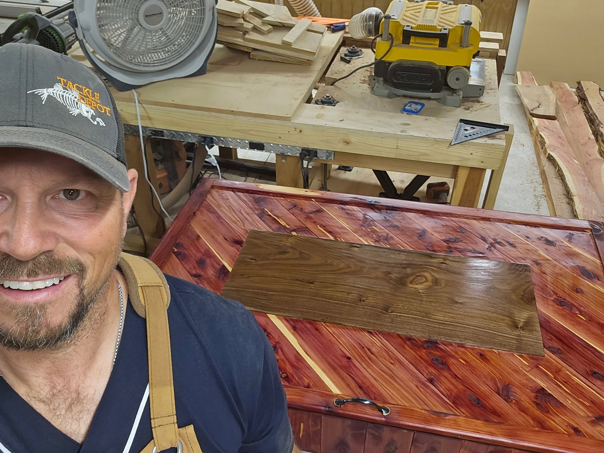 Ham in his workshop with a finished cedar chest and a walnut cutting board