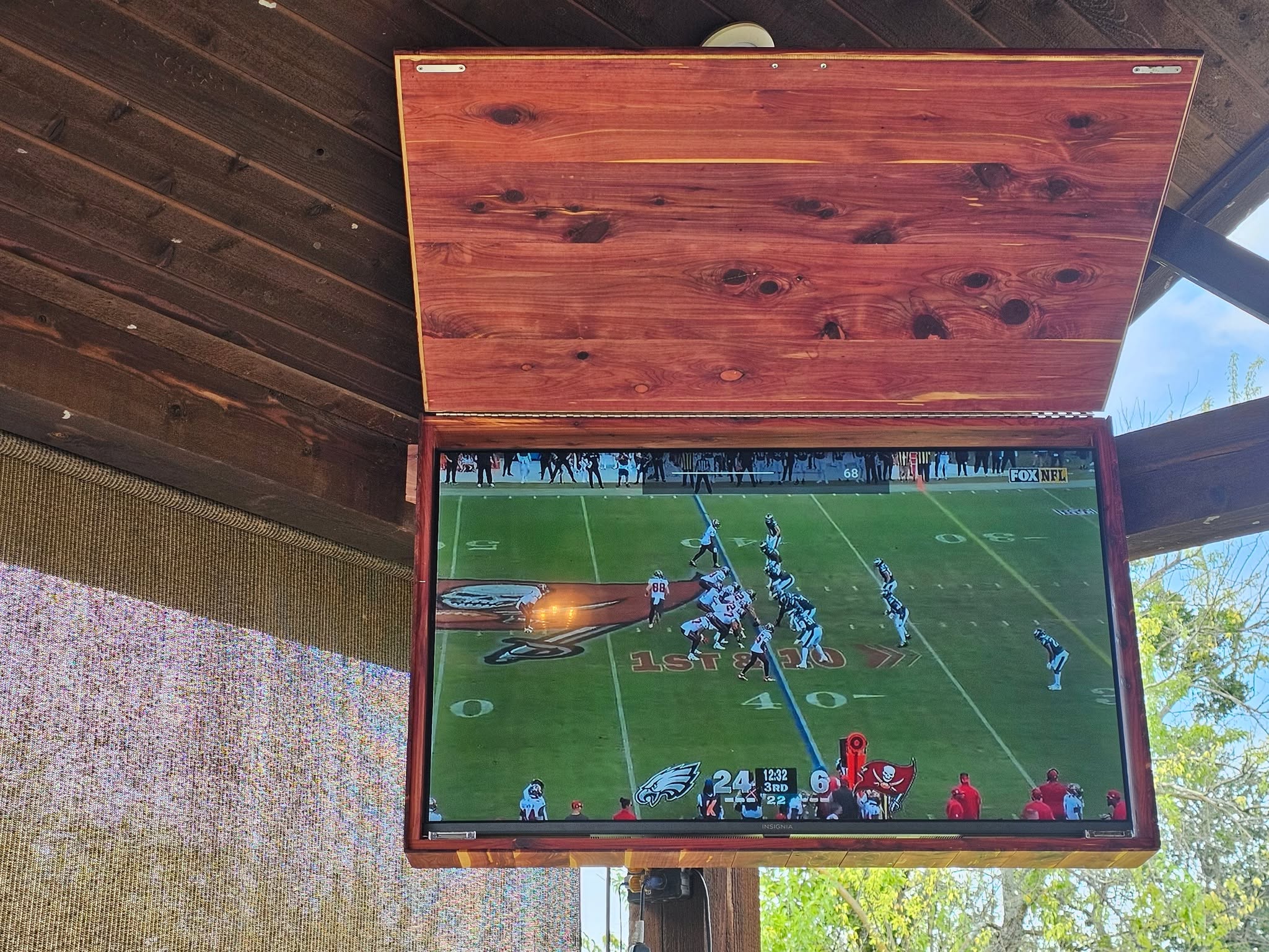 Cedar outdoor TV cabinet mounted on a covered patio